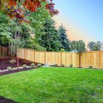 Brown fenced backyard with new planting beds