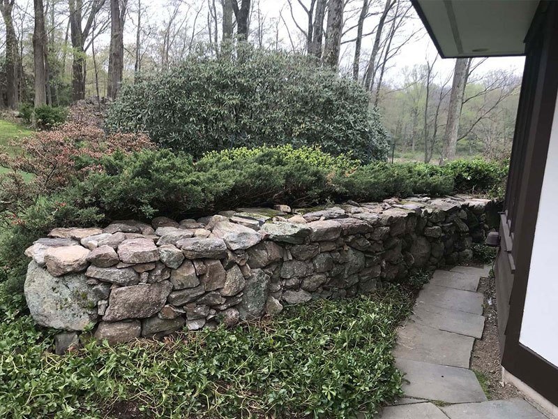 Stone wall with green grass and tress | A-Z Landscaping